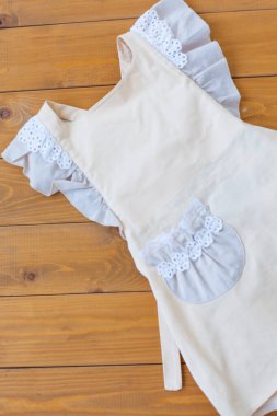 Dantelli önlüklü bej önlükler ve ahşap arka planda bir cep. Genç bir aşçının güzel bir görüntüsü.