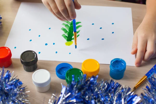 Uma mesa de estudantes com ferramentas de desenho e um caderno, tintas, pincéis para desenhar uma árvore de Natal e um boneco de neve. Desenvolvimento infantil. — Fotografia de Stock