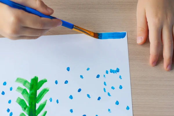 Um menino pinta uma árvore de Natal e neve em um pedaço de papel. Desenho de Ano Novo de crianças. Gouache e pincéis. Desenvolvimento infantil — Fotografia de Stock