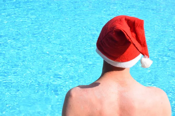 プールのサンタクロースの帽子の男 暖かい国での新年とクリスマスの休日の概念 — ストック写真