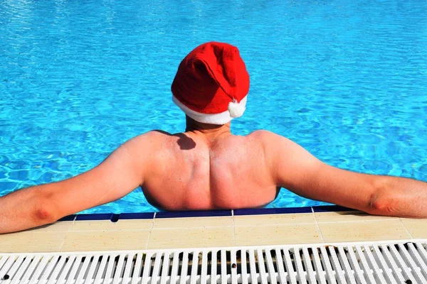 プールのサンタクロースの帽子の男 暖かい国での新年とクリスマスの休日の概念 — ストック写真