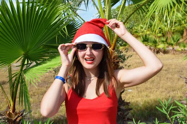 Dziewczyna Kapeluszu Świętego Mikołaja Czerwona Koszulka Tle Zielonych Dłoni Koncepcja — Zdjęcie stockowe