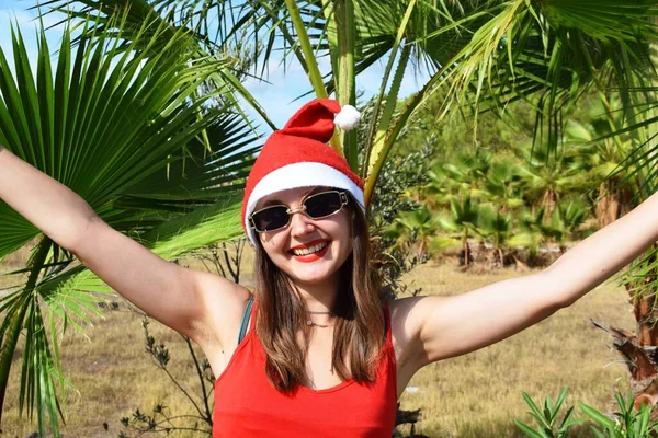Girl Santa Claus Hat Red Shirt Background Green Palms Concept — Stock Photo, Image