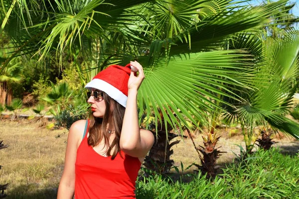 Girl Santa Claus Hat Red Shirt Background Green Palms Concept — Stock Photo, Image