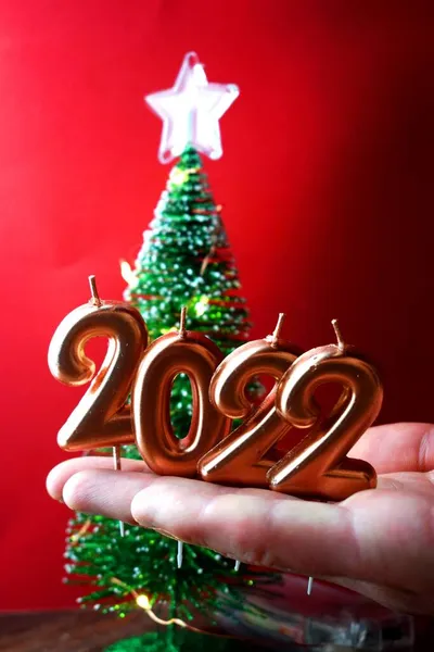 Праздничное Золотое Число 2022 Свечи Рождество Руках Человека Красном Фоне — стоковое фото