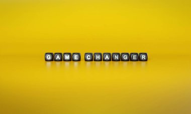 Dönem Oyun Değiştirici düz sarı arkaplan karşı koyu tahta bloklar üzerinde beyaz metin ile hecelenir