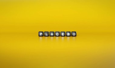 Placebo kelimesi beyaz metinlerle yazılıyor. Sade sarı arka plana karşı koyu ahşap bloklar üzerine.