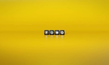 Kısaltma FOMO ya da Eksik Çıkma Korkusu koyu ahşap bloklar üzerinde düz sarı arkaplan üzerinde beyaz metinlerle yazılıyor
