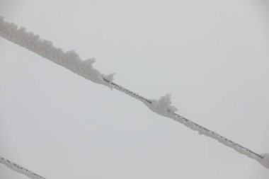 Donmuş güç hattı direkleri. Yüksek voltaj kablolarında ve direklerde buz tabakası var. Dağlarda kış.