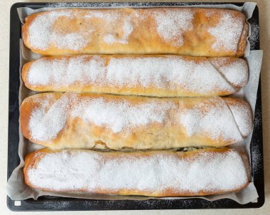 Apple and poppy seed pies lie on a tray from the oven