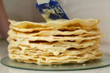 Making homemade Napoleon cake. Many layers of cake smeared with cream