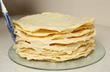 Making homemade Napoleon cake. The sides of the cake are also generously smeared with cream
