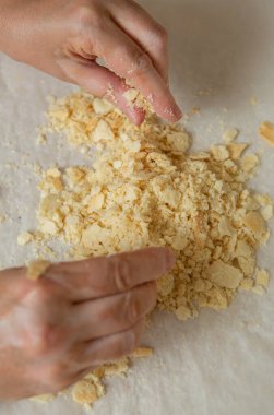 Making homemade Napoleon cake. One layer is broken into small pieces for sprinkling the cake