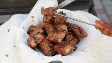Chef removes pieces of fried meat from a skewer onto a plate covered with pita bread