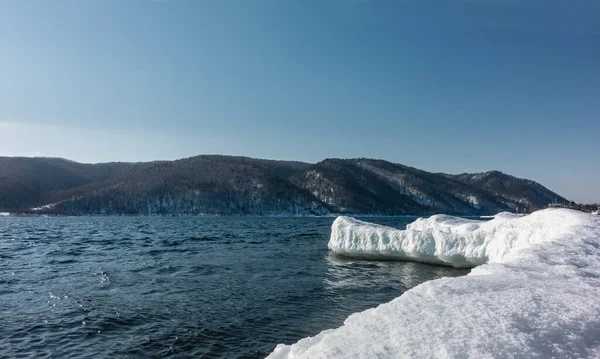 Dondurucu olmayan bir nehrin yatağında buzdan bir humme çıkıntı yapar. Mavi suda dalgalanmalar ve yansımalar. Gök kubbeye karşı bir dağ sırası. Sibirya 'da. Angara.