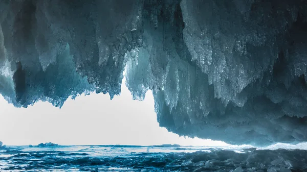 氷の洞窟からの出口はレースのフリルのような青い光沢のあるつららの列に囲まれています 明るい光を先に 凍結湖の表面 バイカル — ストック写真