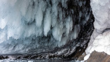 Mağaranın çatısında kalın parlak buz saçakları asılı. Şık bir şekli var. Yakın plan. Baykal..