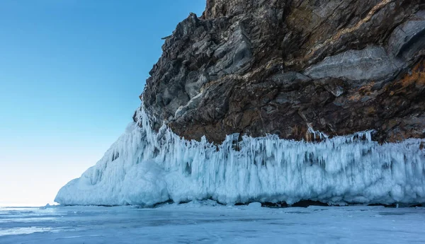 花岗岩的底部没有植被 覆盖着一层厚厚的奇异的冰柱 石头的质地 冰冻湖面上的冰块碎片 蓝天贝加尔湖 — 图库照片
