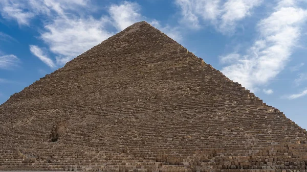 在蓝天的背景上 有着如画般的云彩 形成了一个巨大的奶酪金字塔 在墙上 由古老的巨石制成 你可以看到里面的入口 — 图库照片