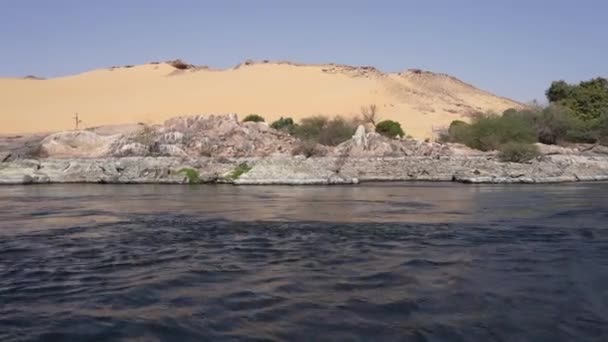青い水が流れている 海岸には砂丘 村の家が見えます 動画はナイル川に浮かぶ船から撮影されています エジプトだ アスワン — ストック動画
