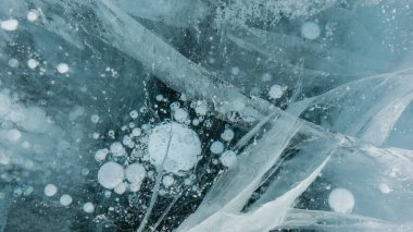 Şeffaf turkuaz buz. Yakın plan. Tam ekran. Ayrıntılar. Kesişen çatlaklar, donmuş metan gazı kabarcıkları görülebilir. Üst Manzara. Baykal.