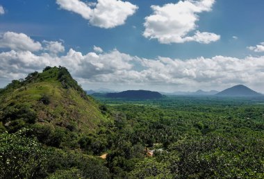 Yoğun sonsuz ormanın üzerinde yeşil dağlar ve tepeler yükselir. Manzaralı bulutlu mavi gökyüzü. Sigirya Dağı 'nın tepesinden panorama. Sri Lanka