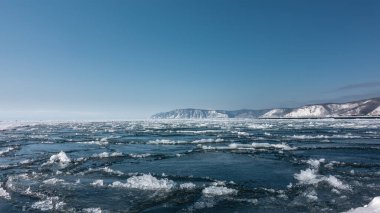 Nehirde buz akıntısı. Mavi buz yüzer ve suyun yüzeyinde erimiş kar olur. Gök maviye karşı karla kaplı bir dağ sırası. Angara. Sibirya