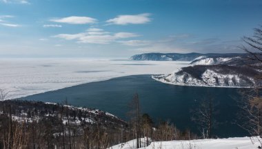 Donmuş bir gölden beyaz buzla kaplı buzsuz mavi bir nehir akar. Kıyılarda ağaçlık dağlar var. Gökte bulutlar var. Baykal ve Angara