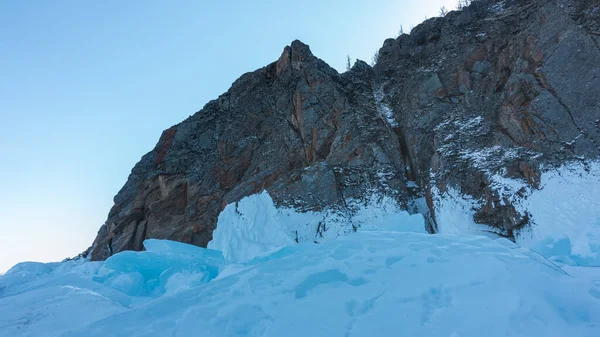 在蓝天的映衬下 一个风景如画的花岗岩岩石 石坡上的裂缝 底部是一块绿松石冰软垫 贝加尔湖 — 图库照片