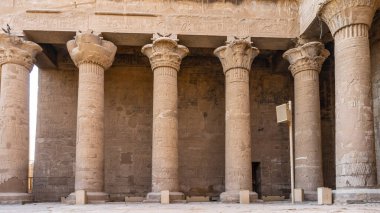 Edfu 'daki Antik Mısır tapınağı Horus' ta Colonnade. Uzun kolonlar ve duvarlar oyulmuş çizimlerle kaplı. Farklı şekillerde zarif başkentler görülebilir..