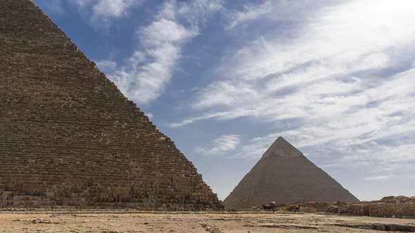 2つの古代エジプトのピラミッド 青い空と雲の背景にあるチープとチェチェン 石積みの壁が見える 足には馬車が描かれている エジプト — ストック写真