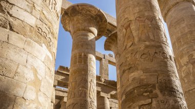 Luxor Karnak Tapınağı 'ndaki antik sütunlar. Yakın plan. Oymalar, hiyeroglifler görünür. Arka plan mavi gökyüzü. Mısır