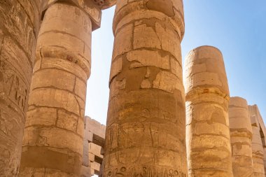 Luxor Karnak Tapınağı 'nın hipotenüs salonunda. Mavi gökyüzüne karşı eski uzun sütunlar. Oymalar ve hiyeroglifler görülebilir. Yakın plan. Mısır