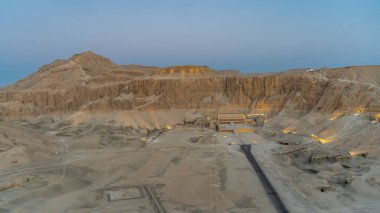 Luxor 'daki Krallar Vadisi' nin havadan görünüşü. Firavun 'un Kraliçesi Hatshepsut' un cenaze kalesi aydınlatıldı. Mavi sabah gökyüzüne karşı pitoresk bir dağ sırası. Mısır