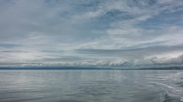 太平洋の光沢のある表面にはさざ波が見える 地平線に 山の範囲と孤独な船 空の絵のような雲 青のパステルカラー カムチャツカ アバチャ湾 — ストック写真