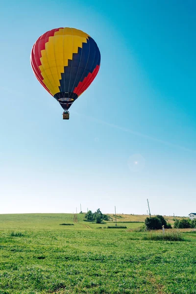 Mavi gökyüzünde çok renkli sıcak hava balonu dikey köy sahasının üzerinde