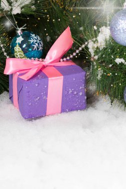 Yılbaşı hediyesi. Ağacın altındaki karda. Metin için de yer var. Dikey kart.