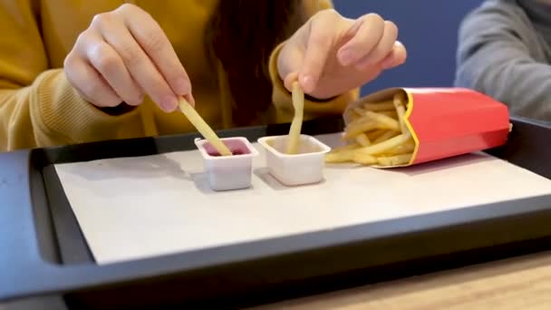 Una mujer en McDonalds come papas fritas, se empapa en dos salsas diferentes. — Vídeo de stock