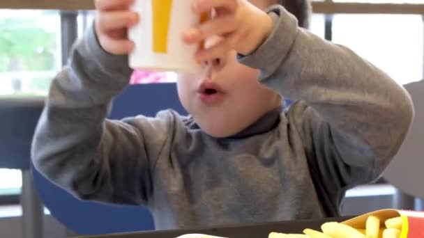 Un niño preescolar bebe jugo de naranja en McDonalds. 03 Octubre 2021, Zaporizhzya, Ucrania. — Vídeos de Stock