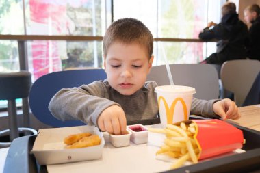 03 Ekim 2021, Zaporizhzya, Ukrayna. 4 yıllık bir çocuk McDonalds 'da patates kızartması, nugget ve portakal suyu yer..