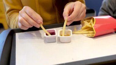 McDonalds 'da bir kadın patates kızartması yer, iki farklı sosta ıslanır. 03 Ekim 2021, Zaporizhzya, Ukrayna.