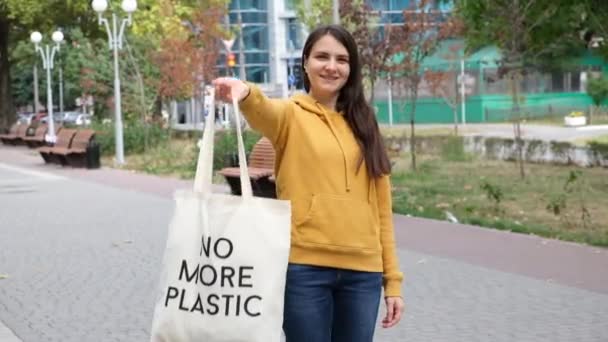 Uma mulher mostra um saco reutilizável de tecido com o texto não mais plástico. — Vídeo de Stock