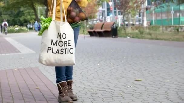 Seorang wanita menempatkan sayuran dan buah-buahan dalam kantong buah dalam tas yang dapat digunakan kembali dengan tulisan tidak lebih plastik — Stok Video