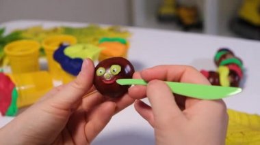 Bir kadın mankenlik ve kestane için hamurdan bir sonbahar sanatı tırtılı yaratır..