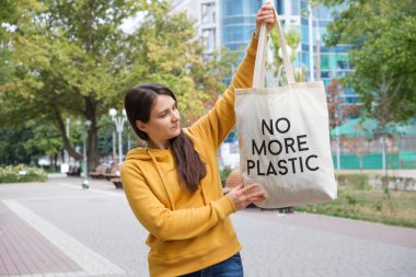 Bir kadın, üzerinde artık plastik olmayan tekrar kullanılabilir bir çanta gösteriyor.