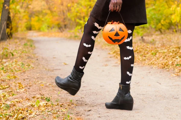 Womens legs in tights with bats walking through the Halloween forest