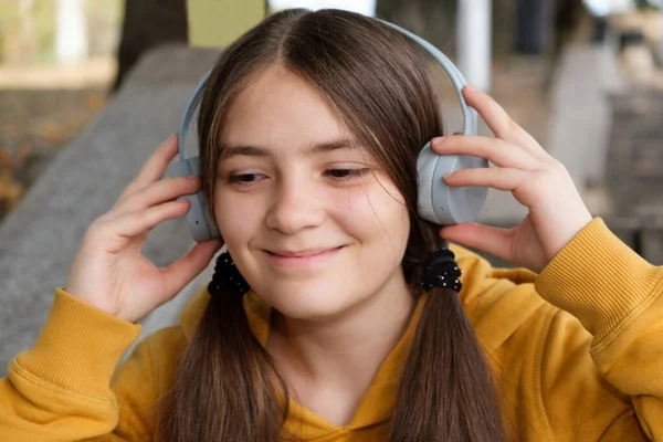13-letnia dziewczynka słucha muzyki ze słuchawkami i uśmiechem, duży portret. — Zdjęcie stockowe