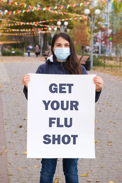 Una mujer con una máscara médica sostiene un póster con el texto — Foto de Stock