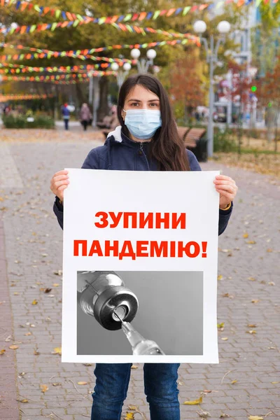 Maskovaná žena s plakátem s nápisem ukrajinsky, přeloženo z ukrajinsky Zastavte pandemii — Stock fotografie