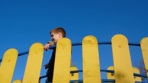 Um menino de 4 anos joga no playground no castelo contra o céu. — Vídeo de Stock